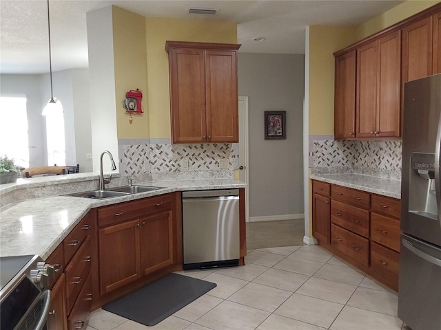 kitchen with appliances with stainless steel finishes, pendant lighting, sink, light tile patterned floors, and light stone countertops