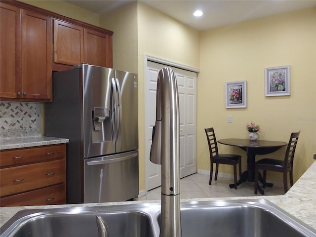 kitchen featuring stainless steel refrigerator with ice dispenser, light tile patterned flooring, and backsplash