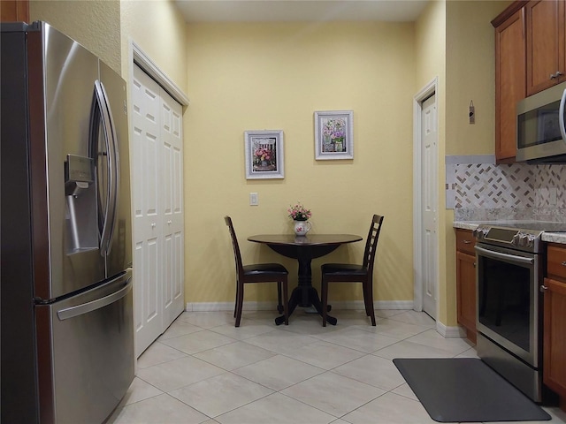 kitchen with tasteful backsplash, appliances with stainless steel finishes, and light tile patterned floors