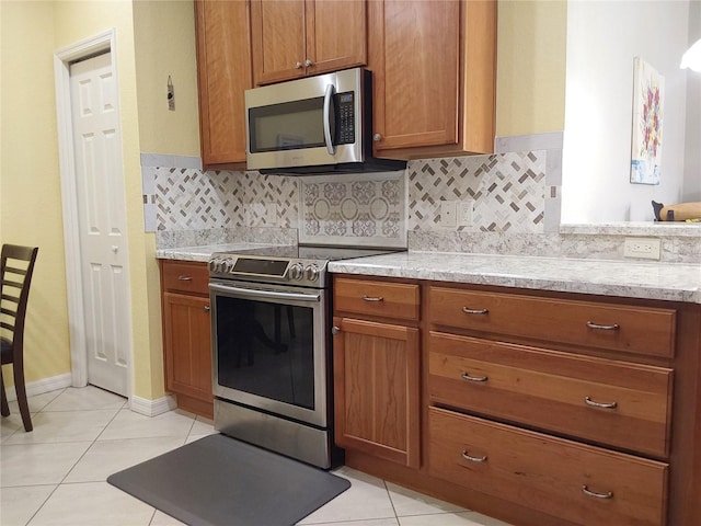 kitchen featuring appliances with stainless steel finishes, light tile patterned floors, and decorative backsplash