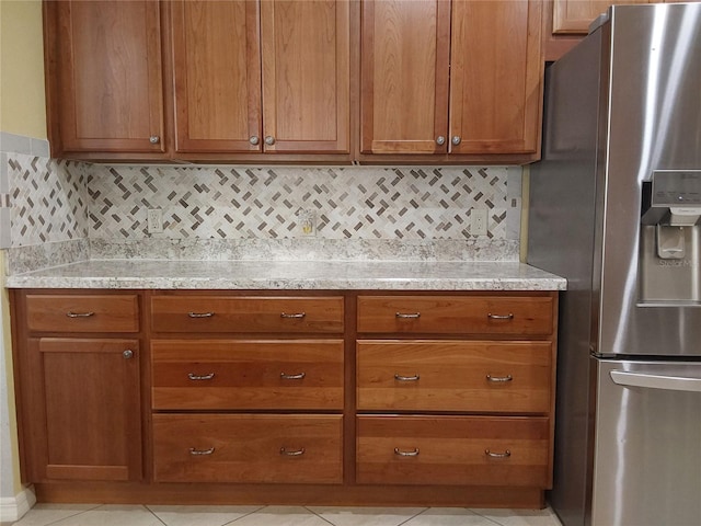 kitchen with tasteful backsplash, light stone countertops, light tile patterned floors, and stainless steel fridge with ice dispenser