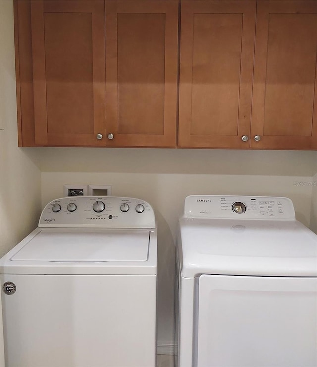 laundry room with washing machine and dryer and cabinets