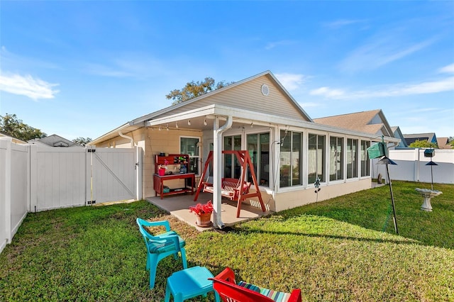 back of house with a lawn, a patio area, and a sunroom