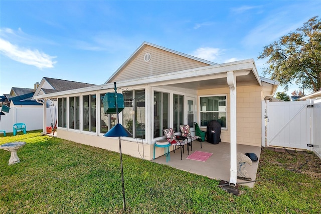 rear view of house featuring a patio, a lawn, and a sunroom