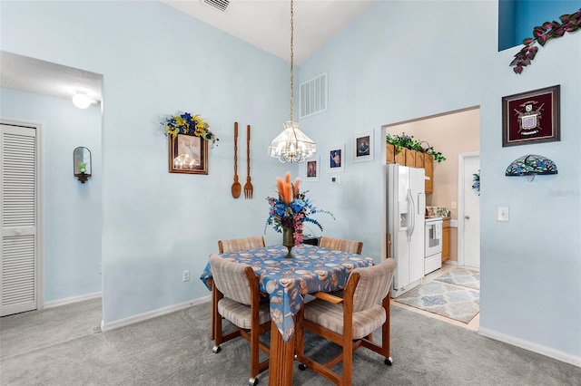 carpeted dining area with high vaulted ceiling and a chandelier