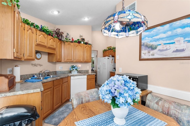 kitchen with white appliances, hanging light fixtures, and sink