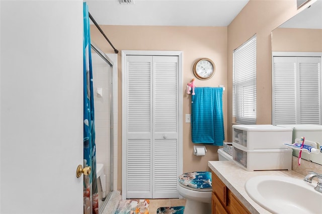 bathroom featuring toilet, vanity, and walk in shower