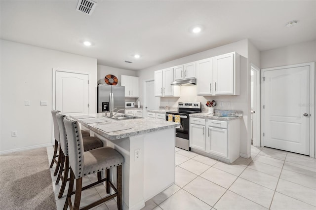 kitchen with white cabinets, stainless steel appliances, an island with sink, and sink