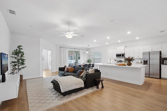 living room featuring light wood-type flooring and ceiling fan