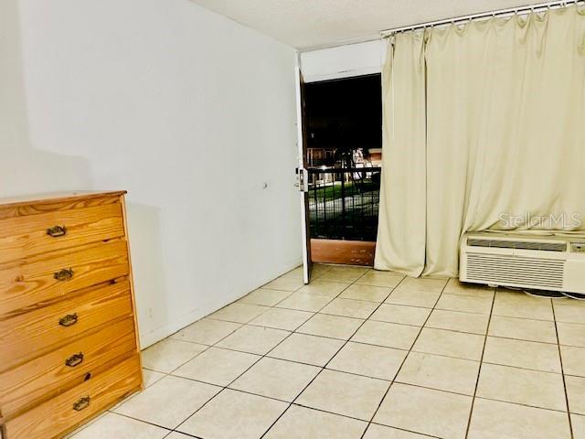 unfurnished room with an AC wall unit and light tile patterned floors