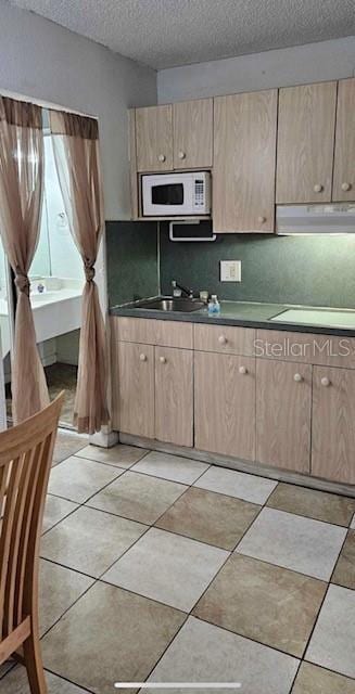 kitchen with light tile patterned floors, sink, backsplash, a textured ceiling, and cooktop