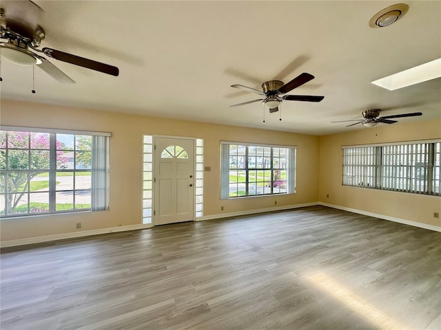 unfurnished living room with light hardwood / wood-style flooring and a skylight