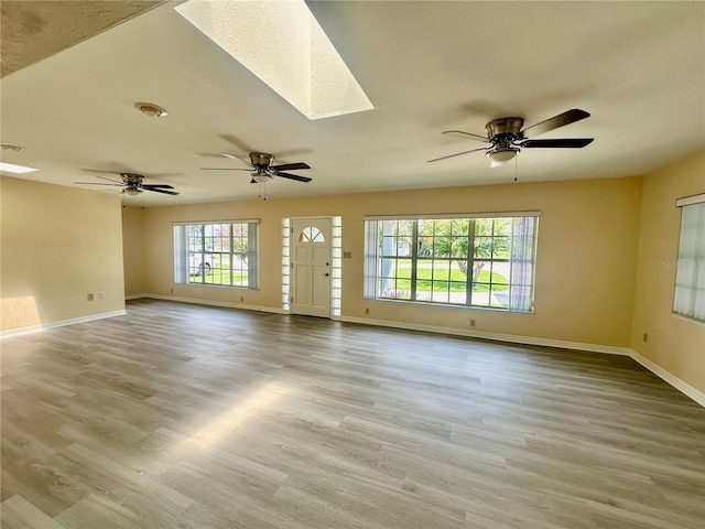 unfurnished living room featuring light hardwood / wood-style flooring and a skylight