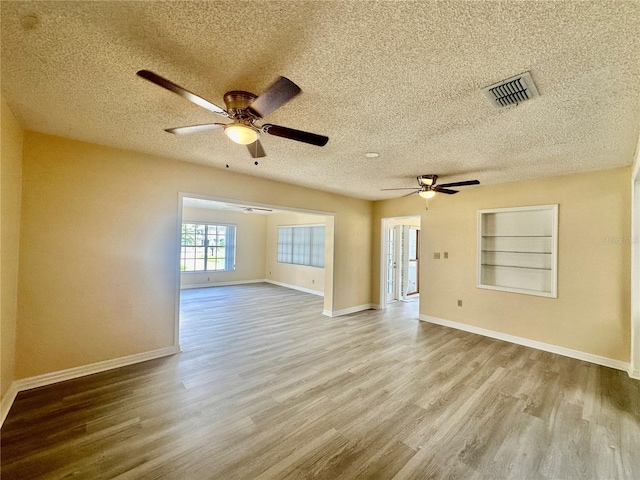 unfurnished room featuring a textured ceiling, light hardwood / wood-style flooring, built in features, and ceiling fan