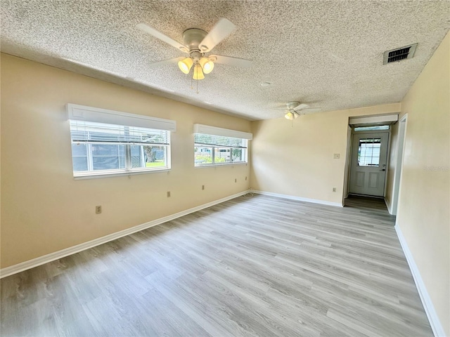 empty room with a textured ceiling, light wood-type flooring, and ceiling fan