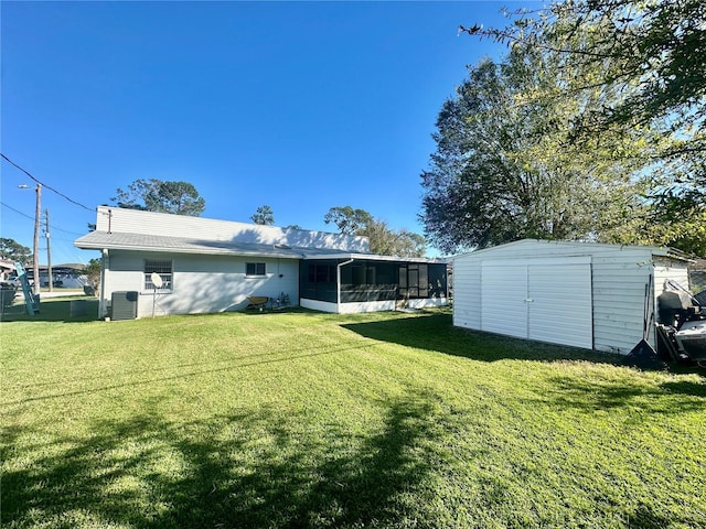 rear view of property featuring a yard, a storage unit, central AC unit, and a sunroom