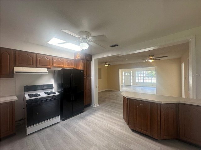 kitchen with light wood-type flooring, black fridge, and gas range gas stove