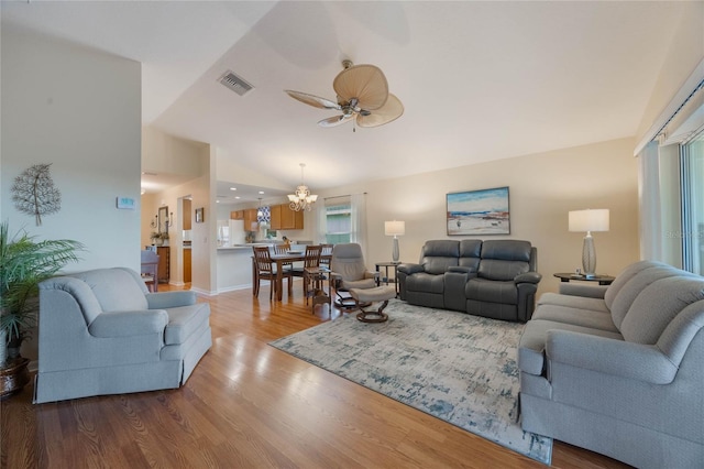 living room featuring ceiling fan with notable chandelier, vaulted ceiling, and hardwood / wood-style floors