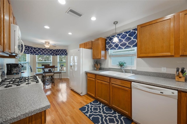 kitchen featuring white appliances, light wood-type flooring, ceiling fan, sink, and decorative light fixtures