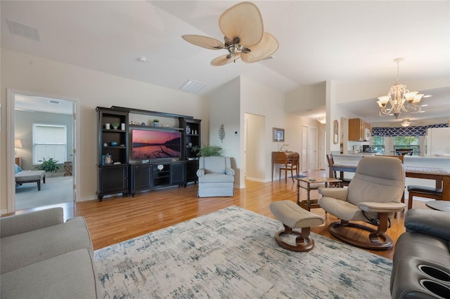 living room with ceiling fan with notable chandelier, lofted ceiling, and light hardwood / wood-style floors