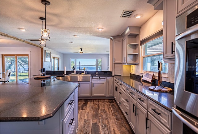 kitchen featuring sink, decorative light fixtures, kitchen peninsula, a wealth of natural light, and dark hardwood / wood-style floors