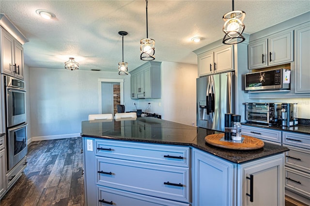 kitchen with a kitchen island, stainless steel appliances, dark hardwood / wood-style floors, and pendant lighting