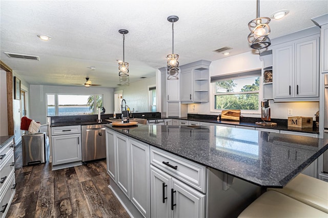 kitchen with a large island with sink, ceiling fan, dishwasher, and pendant lighting