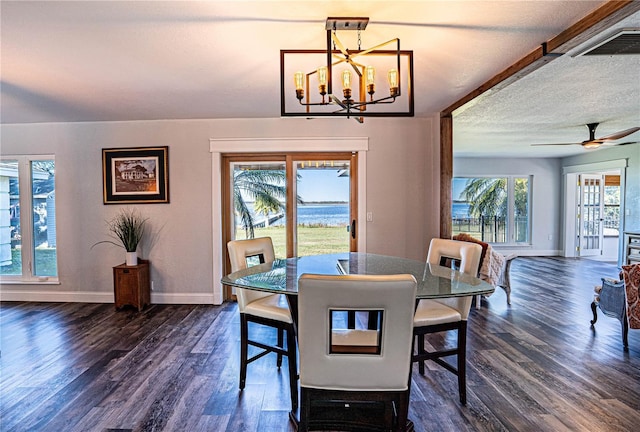 dining area with ceiling fan with notable chandelier, dark wood-type flooring, and plenty of natural light