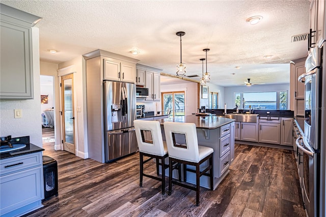 kitchen featuring kitchen peninsula, decorative light fixtures, stainless steel appliances, a kitchen bar, and ceiling fan