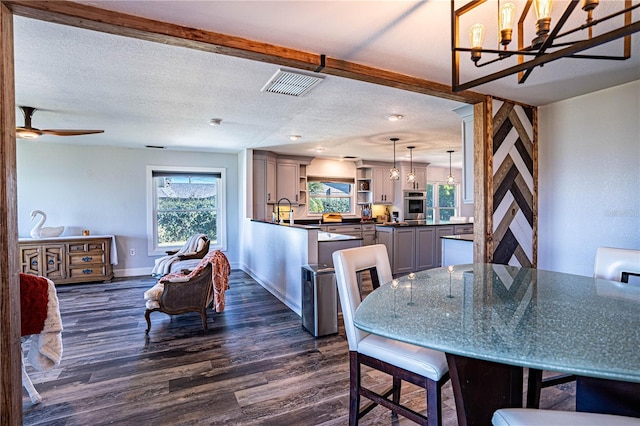 dining room featuring beamed ceiling, a wealth of natural light, dark hardwood / wood-style floors, and a textured ceiling