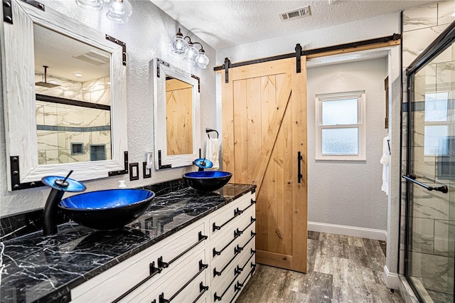 bathroom with vanity, walk in shower, a textured ceiling, and hardwood / wood-style flooring