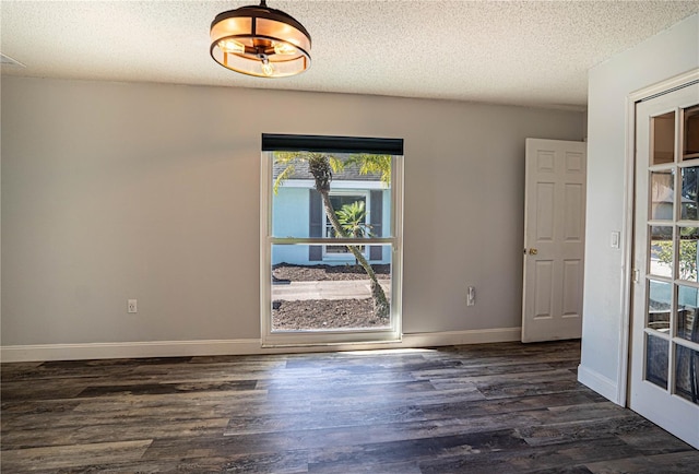 unfurnished room with a textured ceiling, dark wood-type flooring, and plenty of natural light