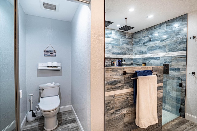 bathroom with tile walls, tiled shower, hardwood / wood-style floors, and toilet