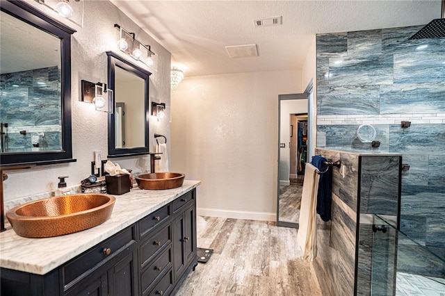 bathroom with a textured ceiling, walk in shower, vanity, and hardwood / wood-style flooring