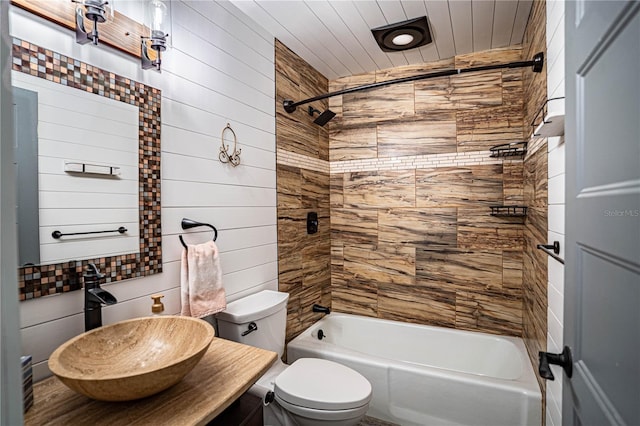 full bathroom featuring toilet, wooden walls, vanity, and tiled shower / bath combo