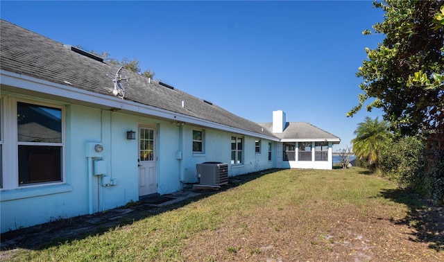 back of property featuring cooling unit, a yard, and a sunroom