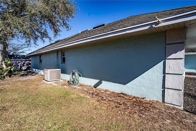 view of side of property with a yard and central AC