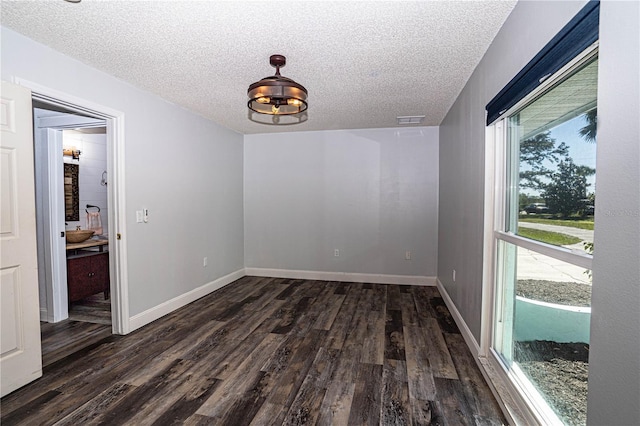 empty room with dark hardwood / wood-style flooring and a textured ceiling