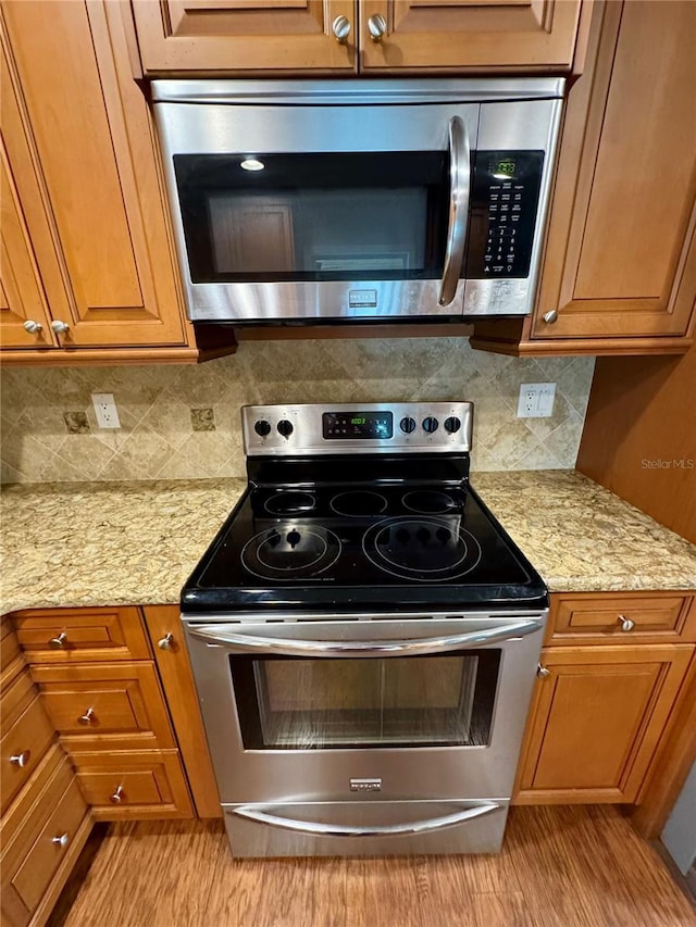 kitchen featuring light stone counters, backsplash, and stainless steel appliances