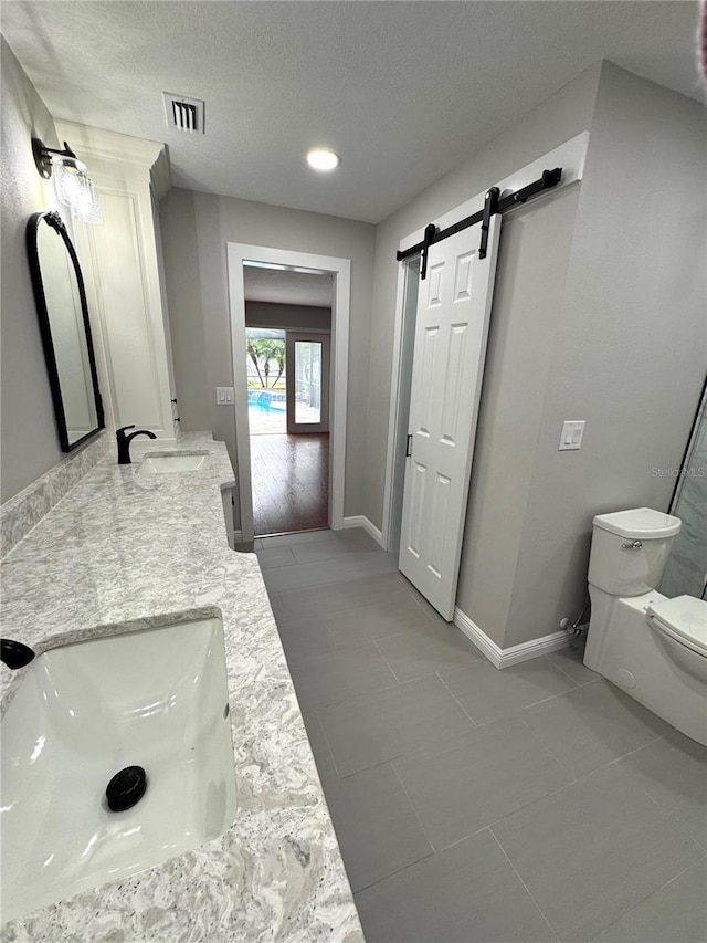 bathroom featuring tile patterned flooring, vanity, a textured ceiling, and toilet