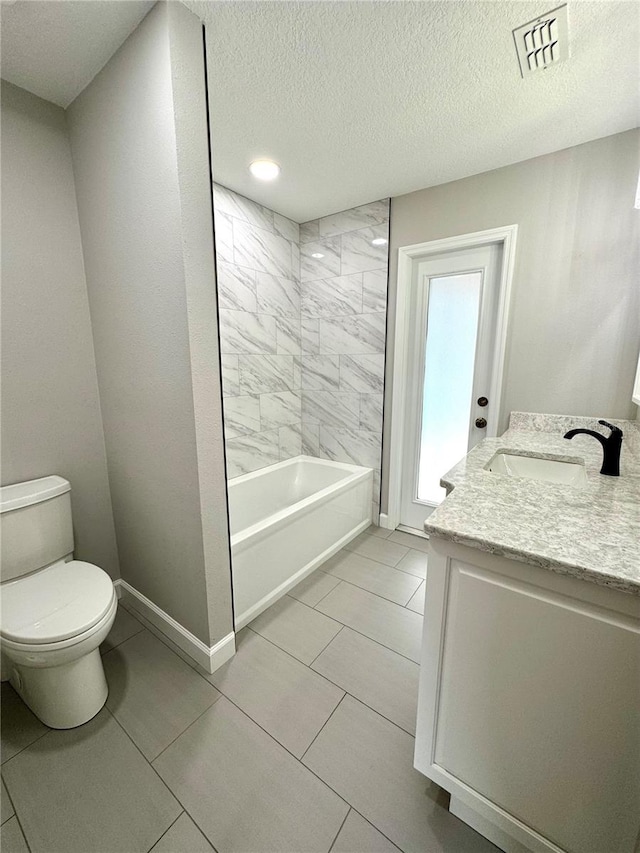 full bathroom featuring tiled shower / bath, vanity, toilet, tile patterned floors, and a textured ceiling