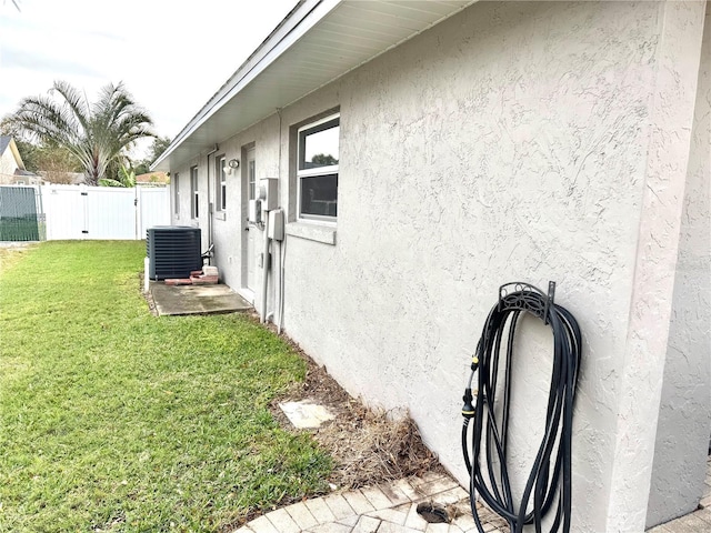 view of side of home with a lawn and central air condition unit