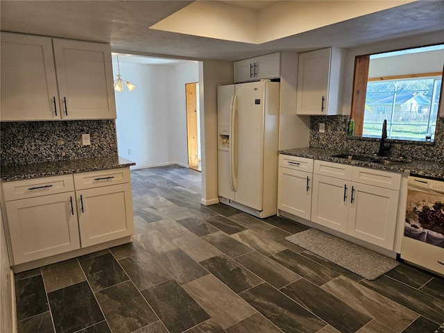 kitchen featuring white cabinetry, white appliances, sink, and dark stone counters