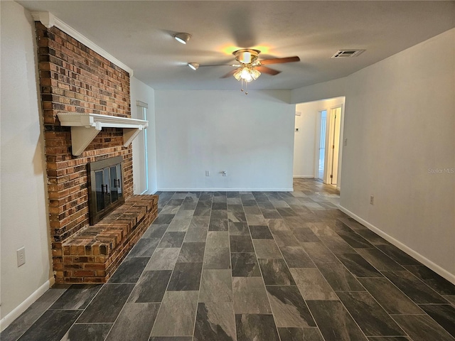 unfurnished living room featuring ceiling fan and a brick fireplace