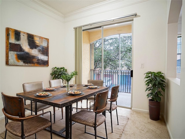 carpeted dining area with crown molding