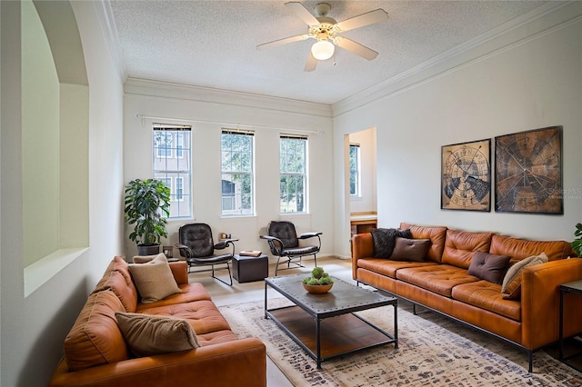 living room with ceiling fan, crown molding, and a textured ceiling