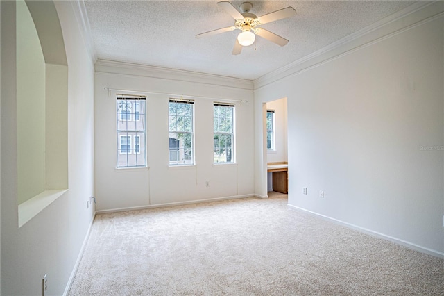 carpeted spare room with ceiling fan, a textured ceiling, and crown molding