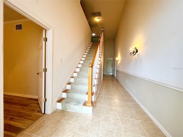 stairway with ornamental molding and tile patterned flooring