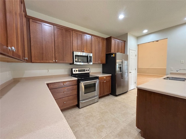 kitchen featuring a textured ceiling, stainless steel appliances, and sink