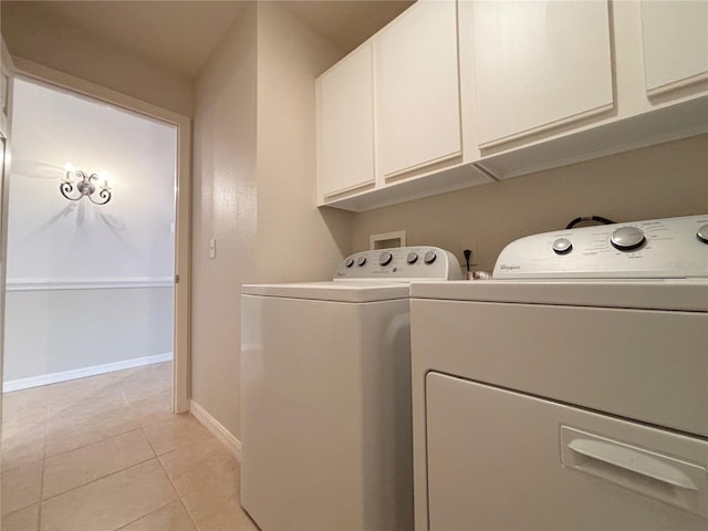 washroom featuring light tile patterned floors, washing machine and clothes dryer, and cabinets